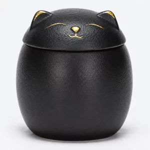 Close view of textured black cat urn with gold sleeping face
