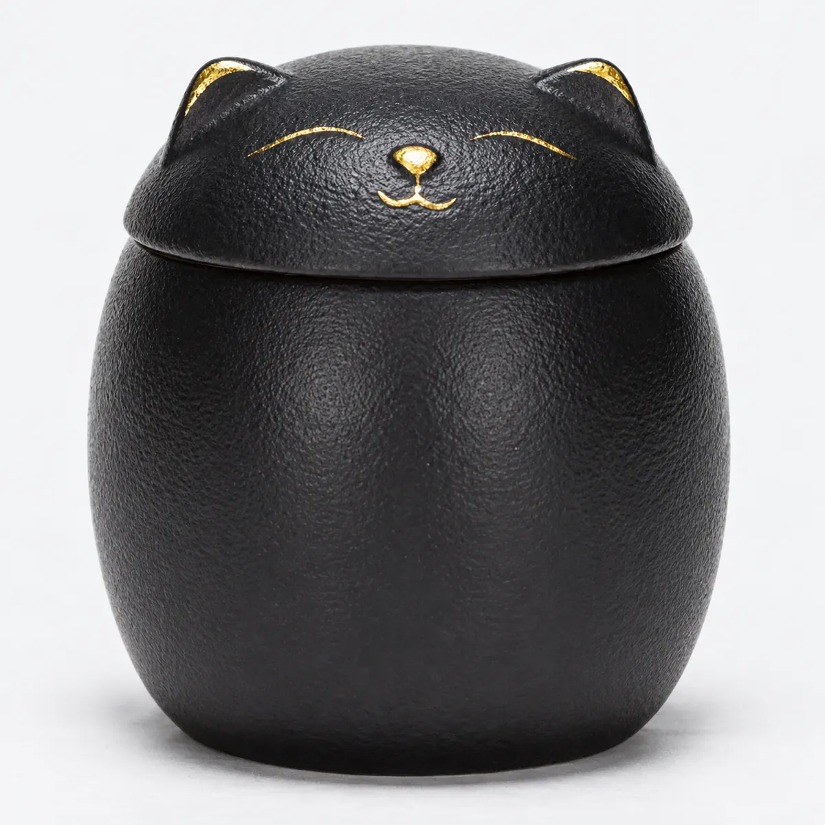 Close view of textured black cat urn with gold sleeping face