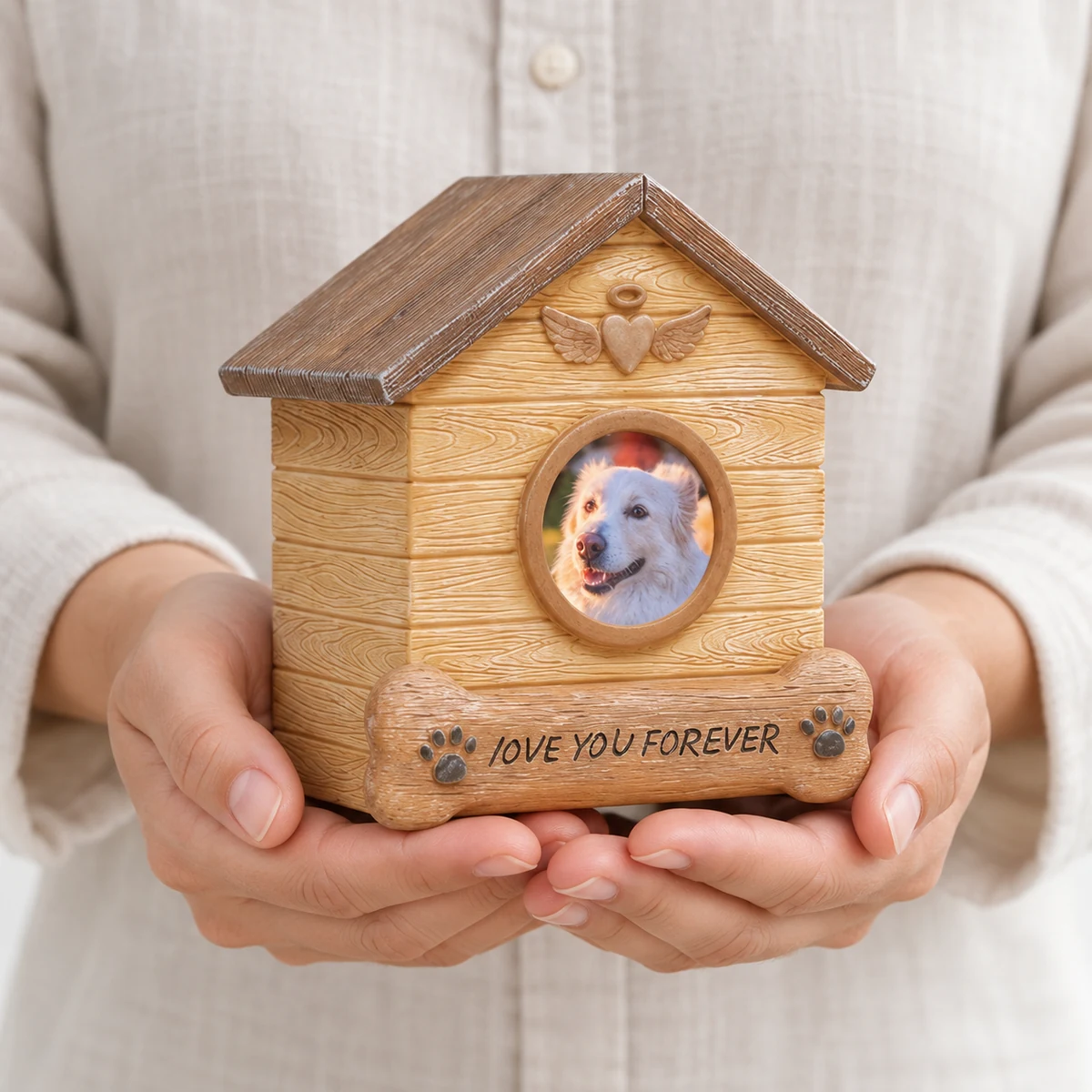 Hands holding a small dog house pet urn with a round photo frame