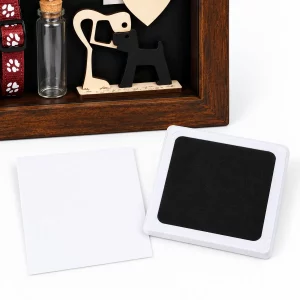 Unused black paw impression pad and blank white card beside dog memorial shadow box