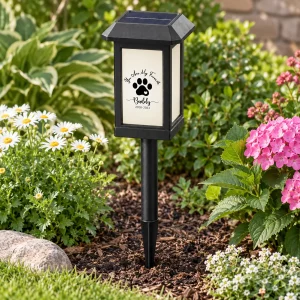 Paw-print solar pet memorial light installed in a flower garden during the day