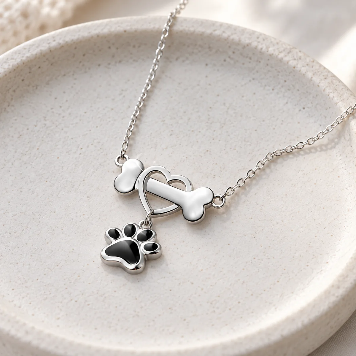 Sterling Silver Dog Bone Necklace with Heart and Paw, on a jewelry tray