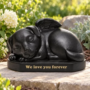 Black sleeping angel dog urn sculpture on a flat garden paver beside flowers