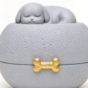 Close view of the sleeping puppy, textured gray surface and gold bone accent
